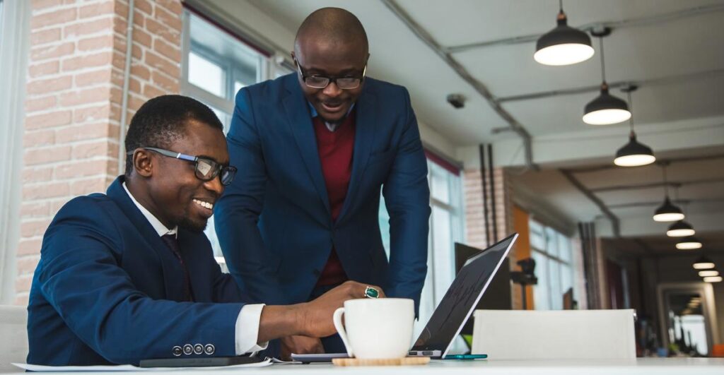 Two African technology professionals building an AI solution together at a laptop in a modern office.